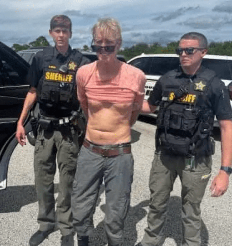 罗斯被锁上手铐带走时似乎在对着警员微笑。 罗斯被锁上手铐带走时似乎在对着警员微笑。
