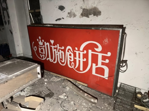 经典“红底”凯施饼店的照牌被放地上（图片：“穷游废墟”FB专页）