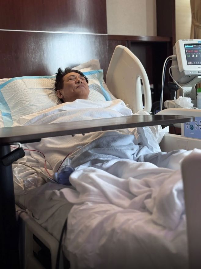 李连杰躺在病床双眼紧闭，露出痛苦神情。